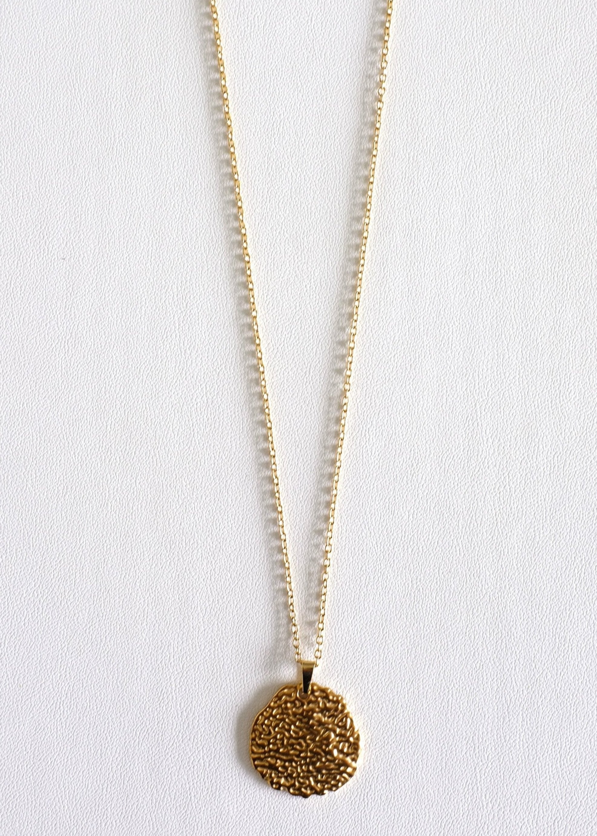 A gold stainless steel crater pendant on a chain, displayed on a white background.