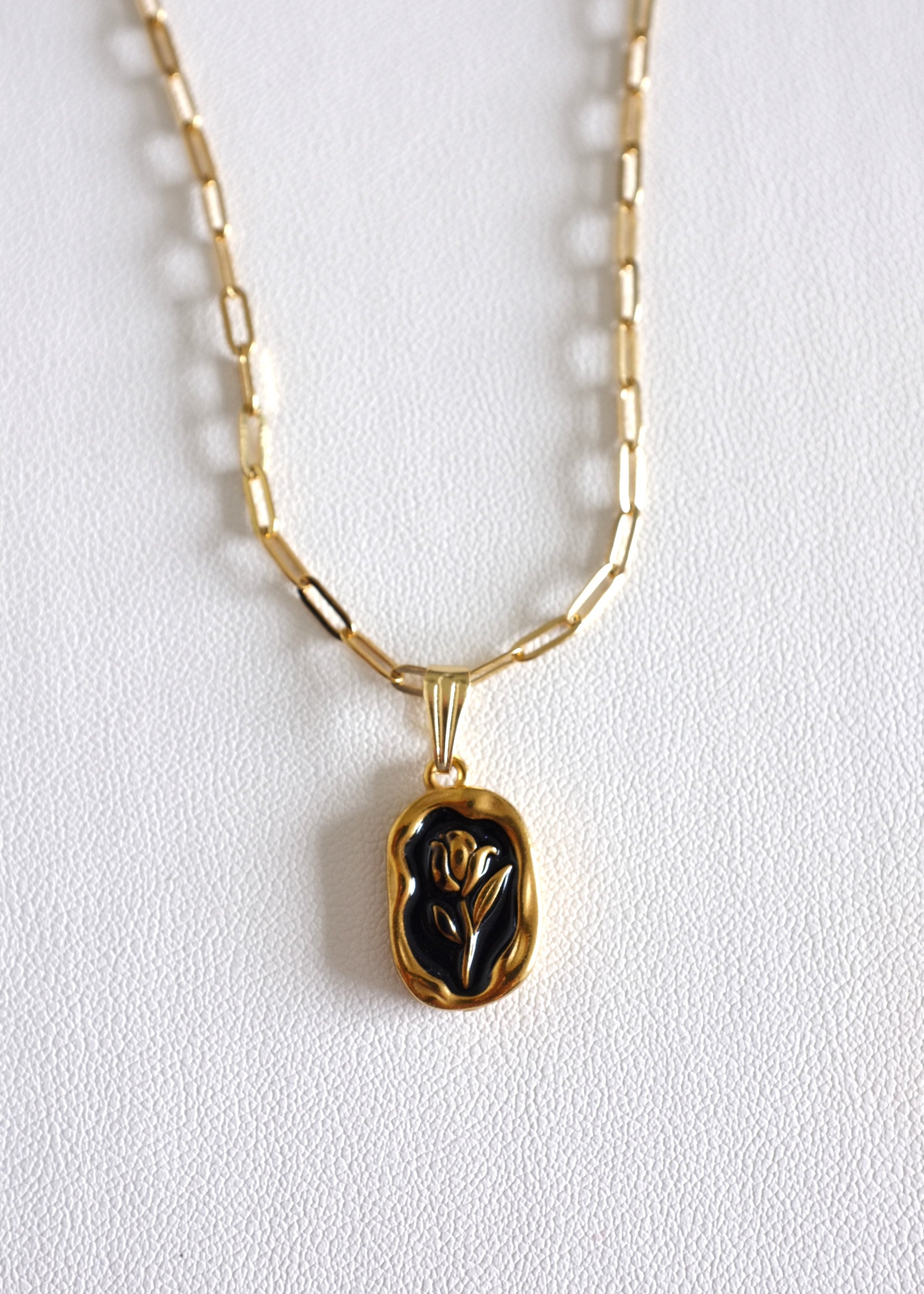 gold stainless steel paperclip chain with a back enamel tulip charm on white background
