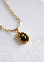 close up of gold stainless steel paperclip chain with a back enamel tulip charm on white background