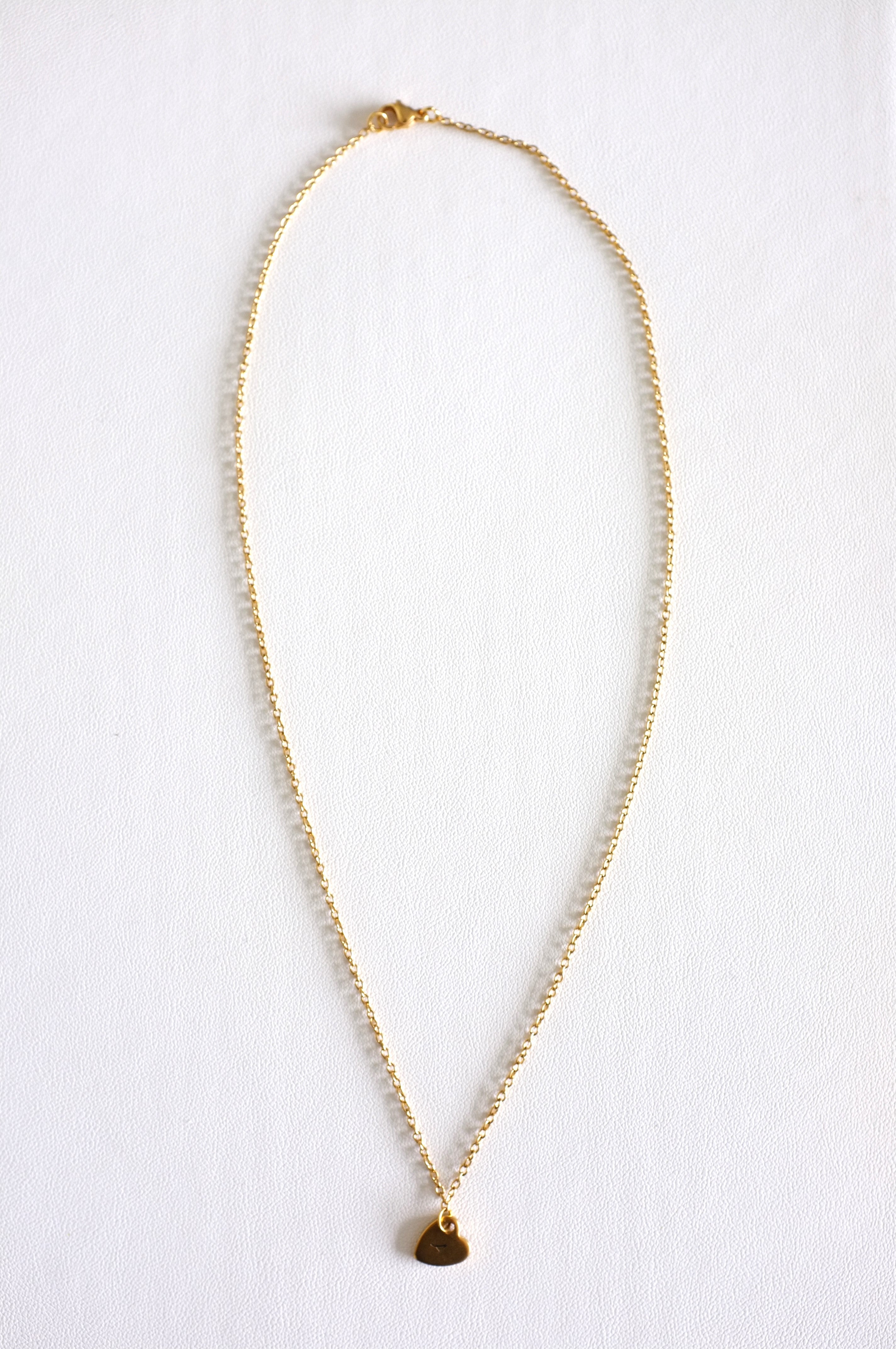 gold stainless steel chain with a small stamped heart charm on white background