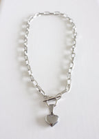 A stainless steel chain necklace with a heart-shaped pendant, displayed on a white background.