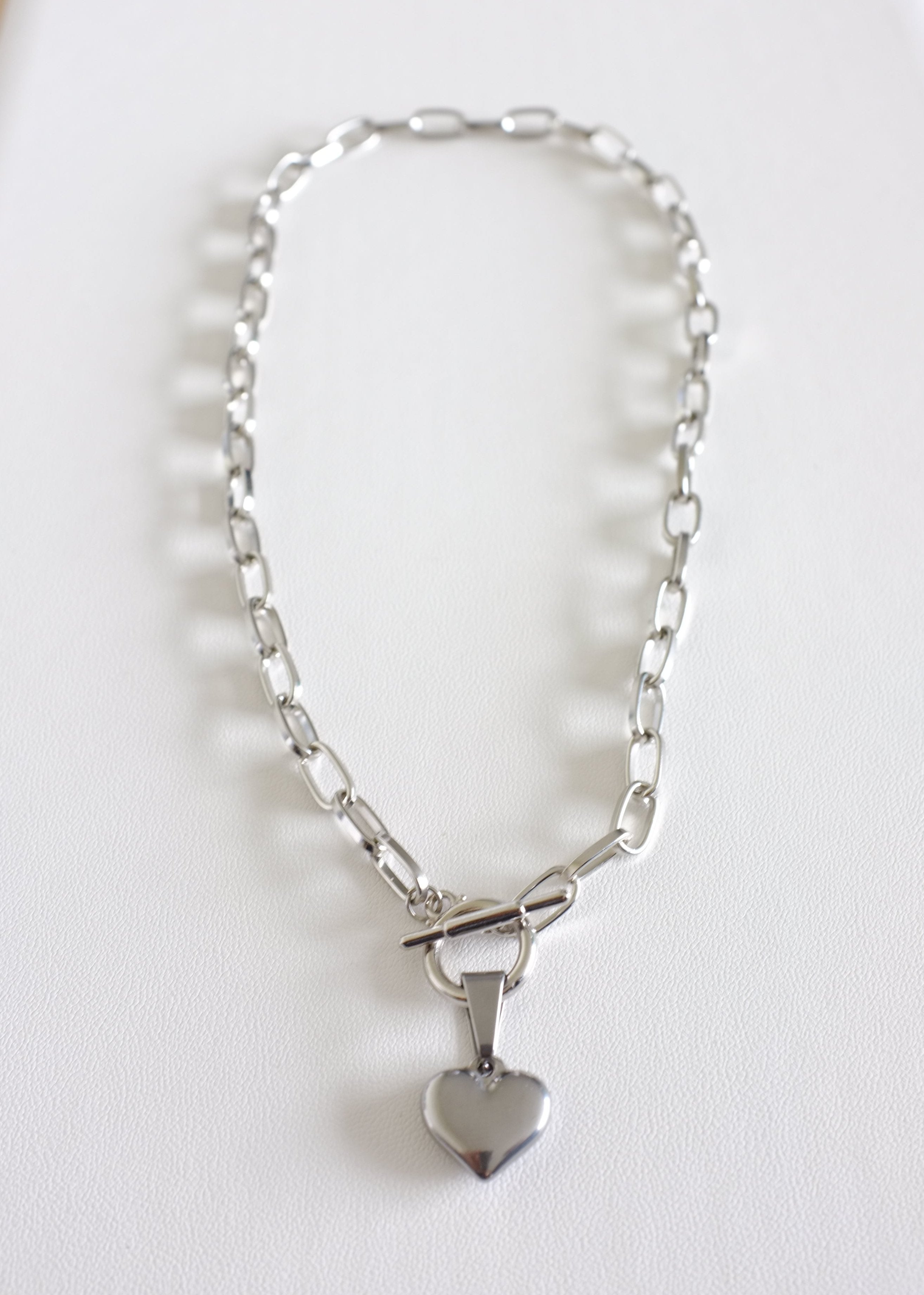 A stainless steel chain necklace with a heart-shaped pendant, displayed on a white background.