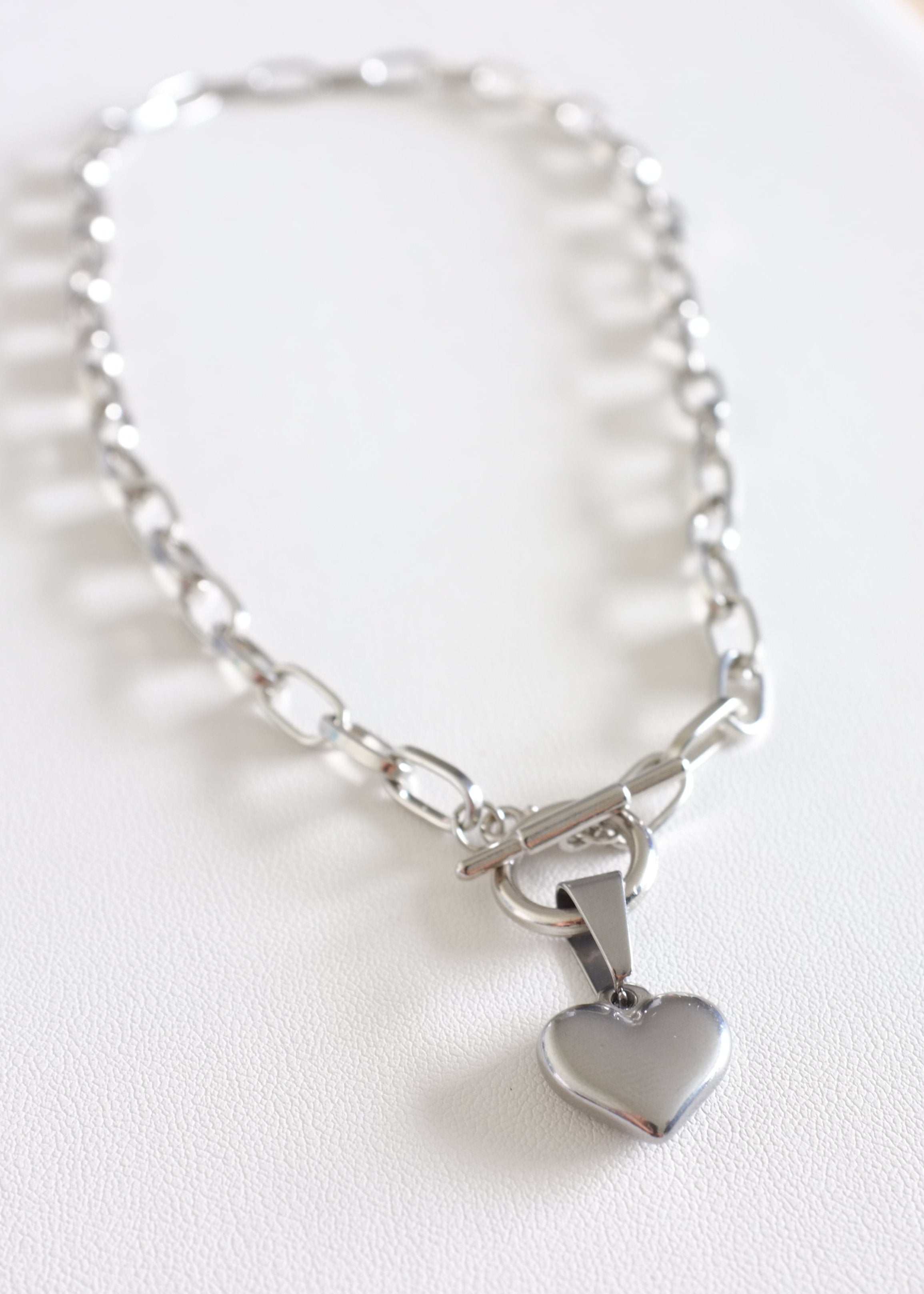 A stainless steel chain necklace with a heart-shaped pendant, displayed on a white background.