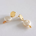 close up of a pair of stainless steel hoop earrings with pearl shell design, displayed against a white background.