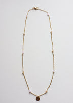 A gold-colored stainless steel chain necklace with multicolor bicone glass beads and a round engravable pendant.