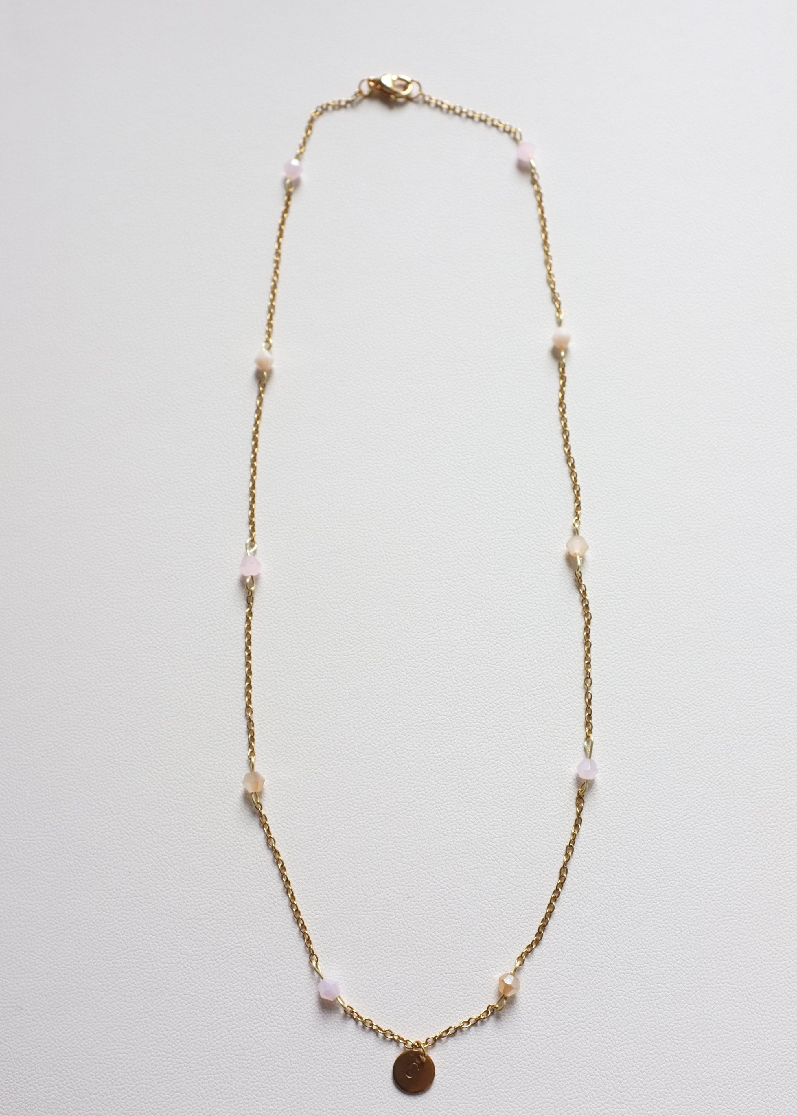 A gold-colored stainless steel chain necklace with multicolor bicone glass beads and a round engravable pendant.