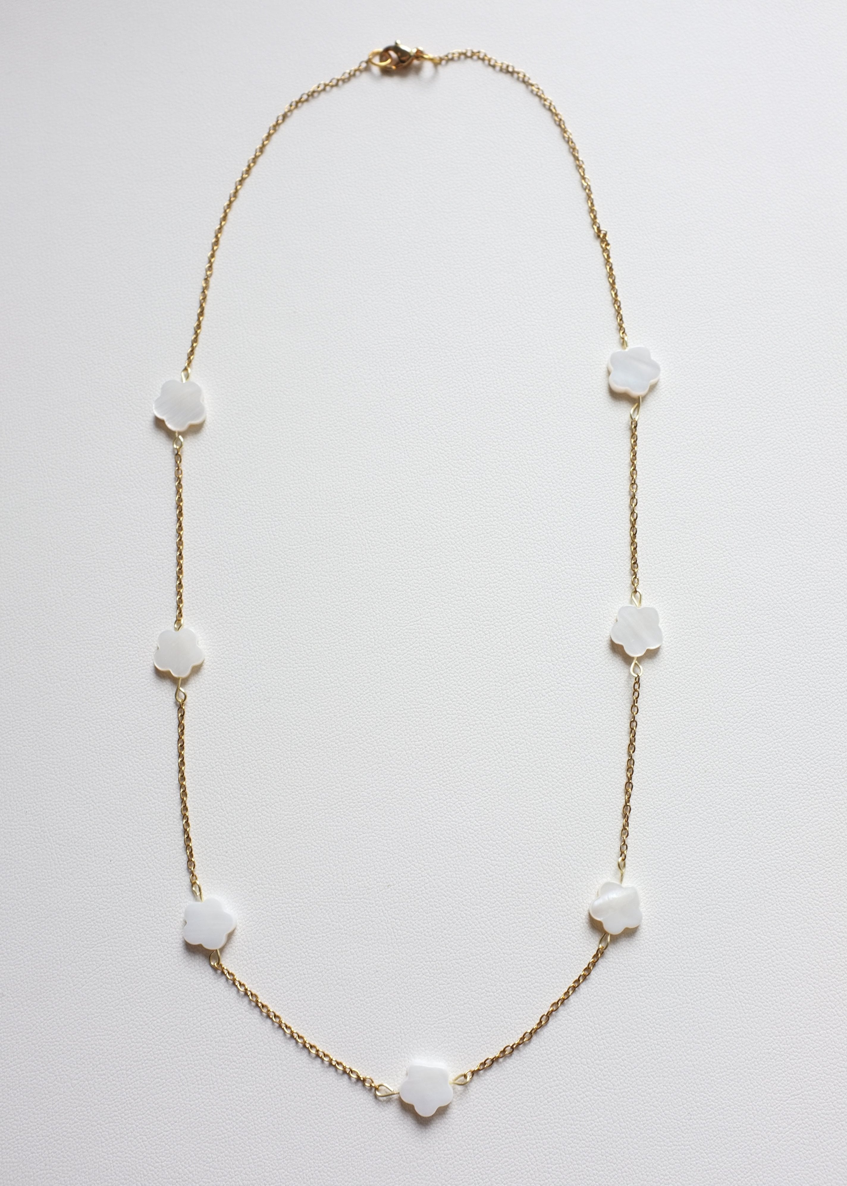 A stainless steel chain necklace with freshwater shell flower beads, featuring a gold-tone chain and white beads.