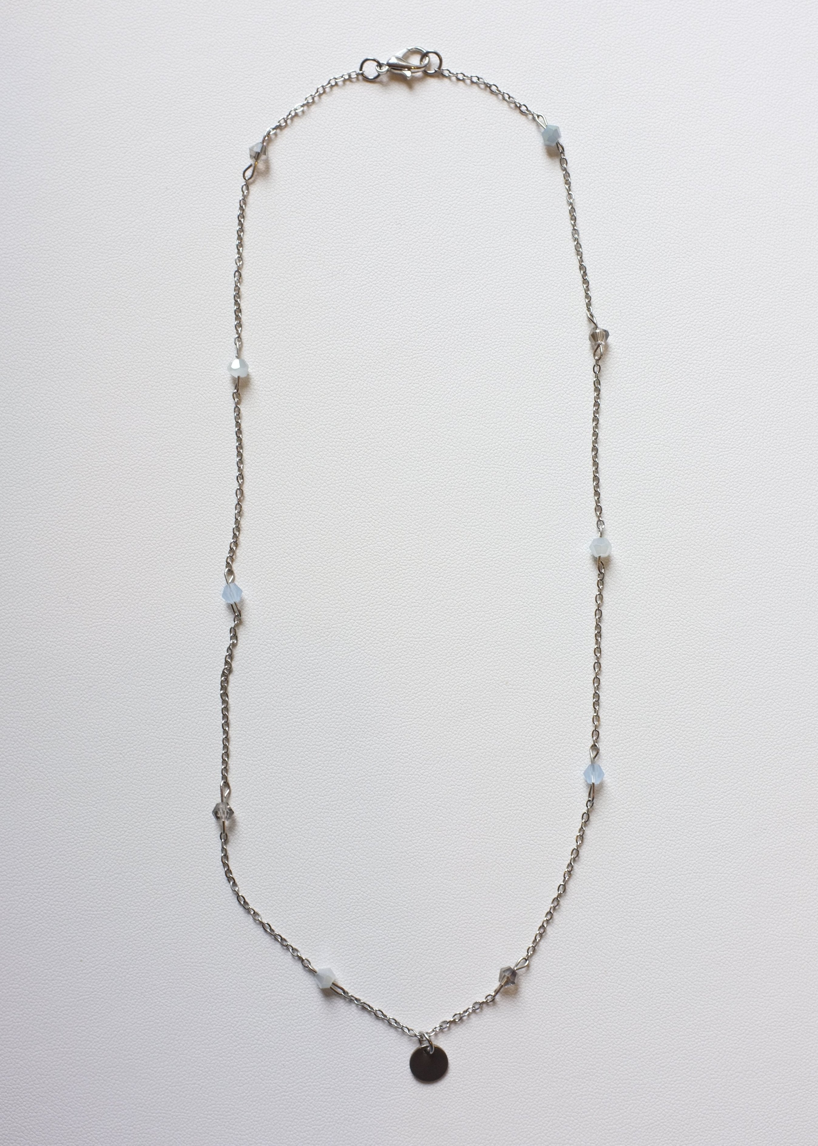 A silver-colored stainless steel chain necklace with multicolor bicone glass beads and a round engravable pendant.