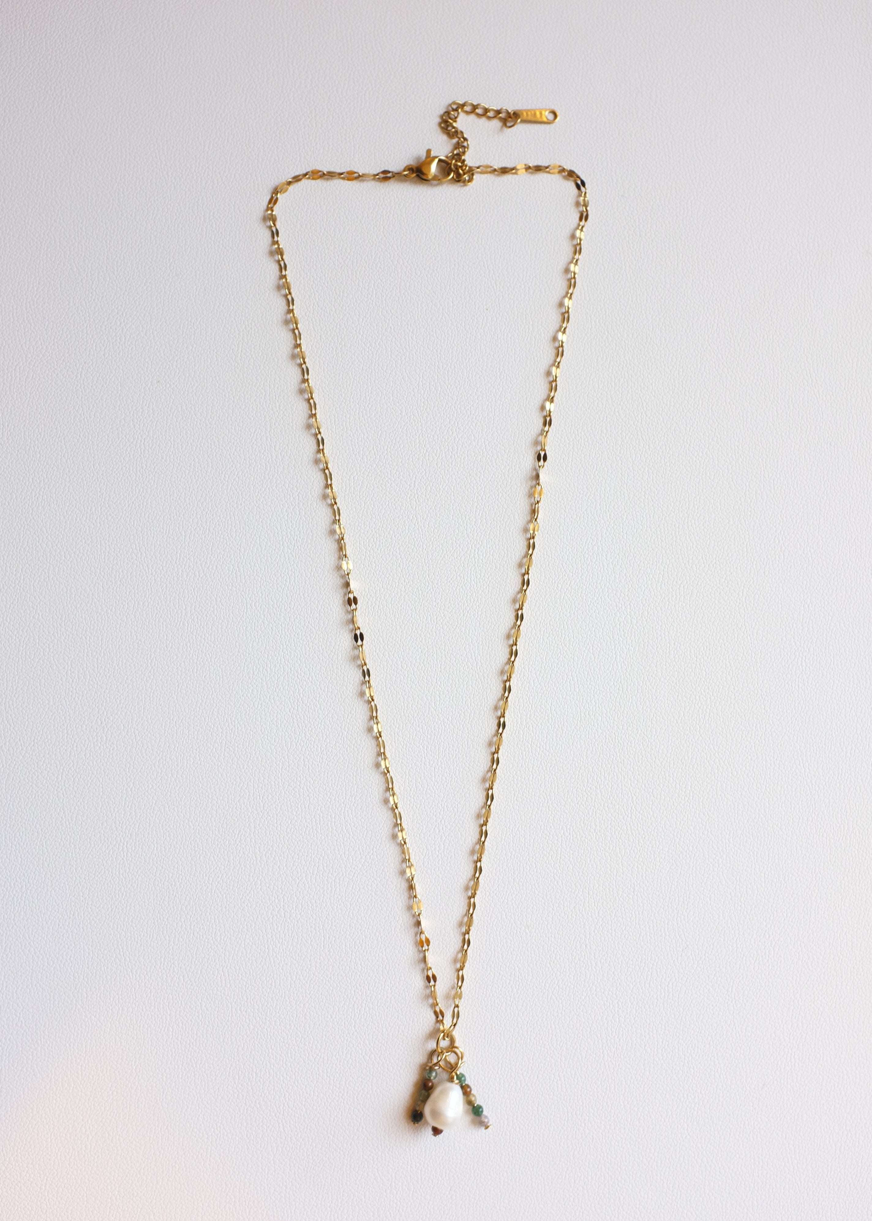 gold stainless steel chain necklace with idian agates charms with a freshwater pearl on white background
