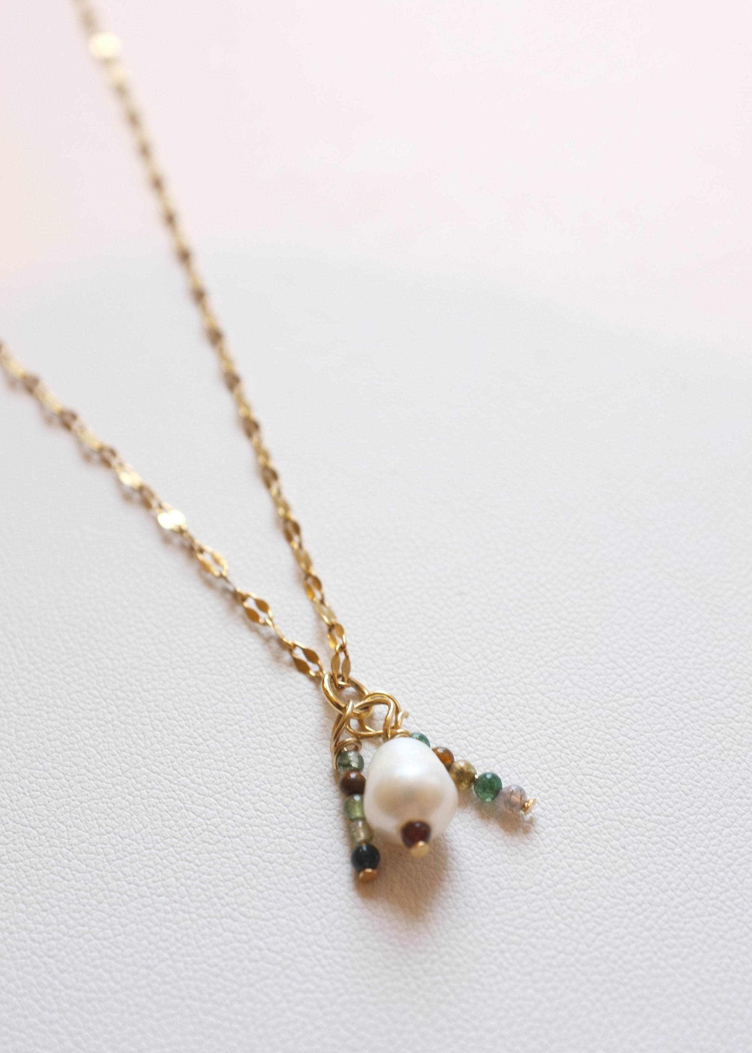 A gold-colored stainless steel necklace with a freshwater pearl pendant and two small pendants with Indian Agate beads.
