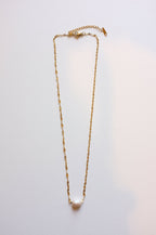 gold stainless steel necklace with one freshwater pearl on white background