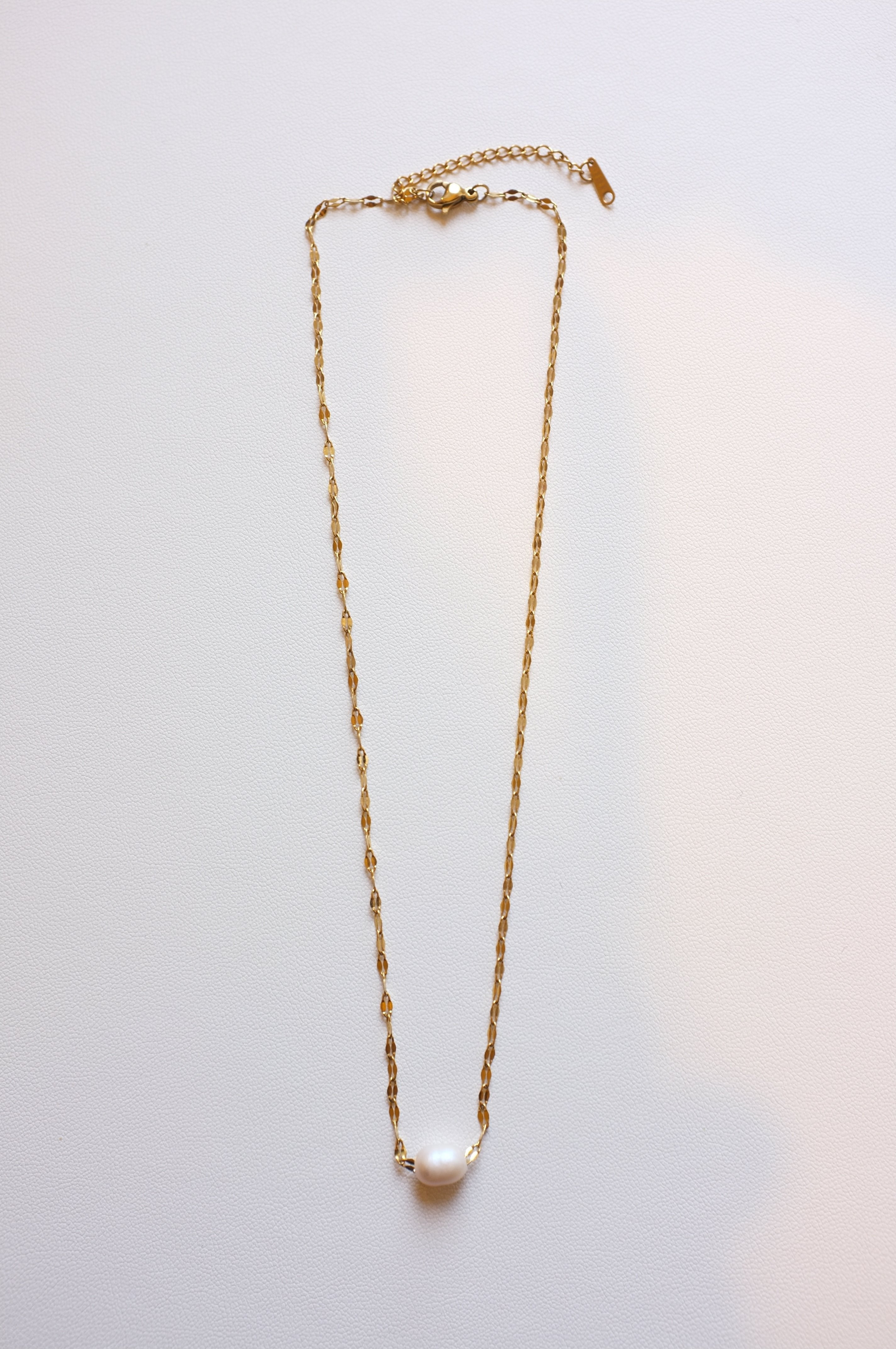 gold stainless steel necklace with one freshwater pearl on white background