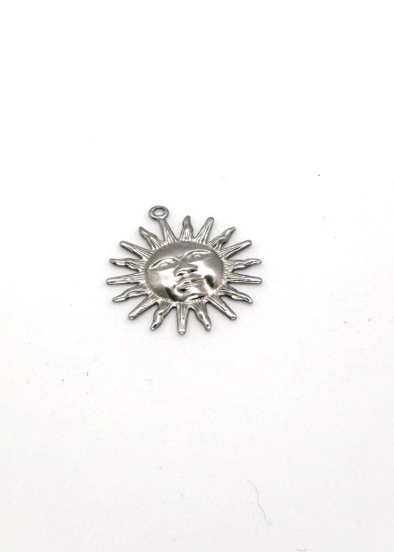 Silver sun-shaped charm with face design on a white background