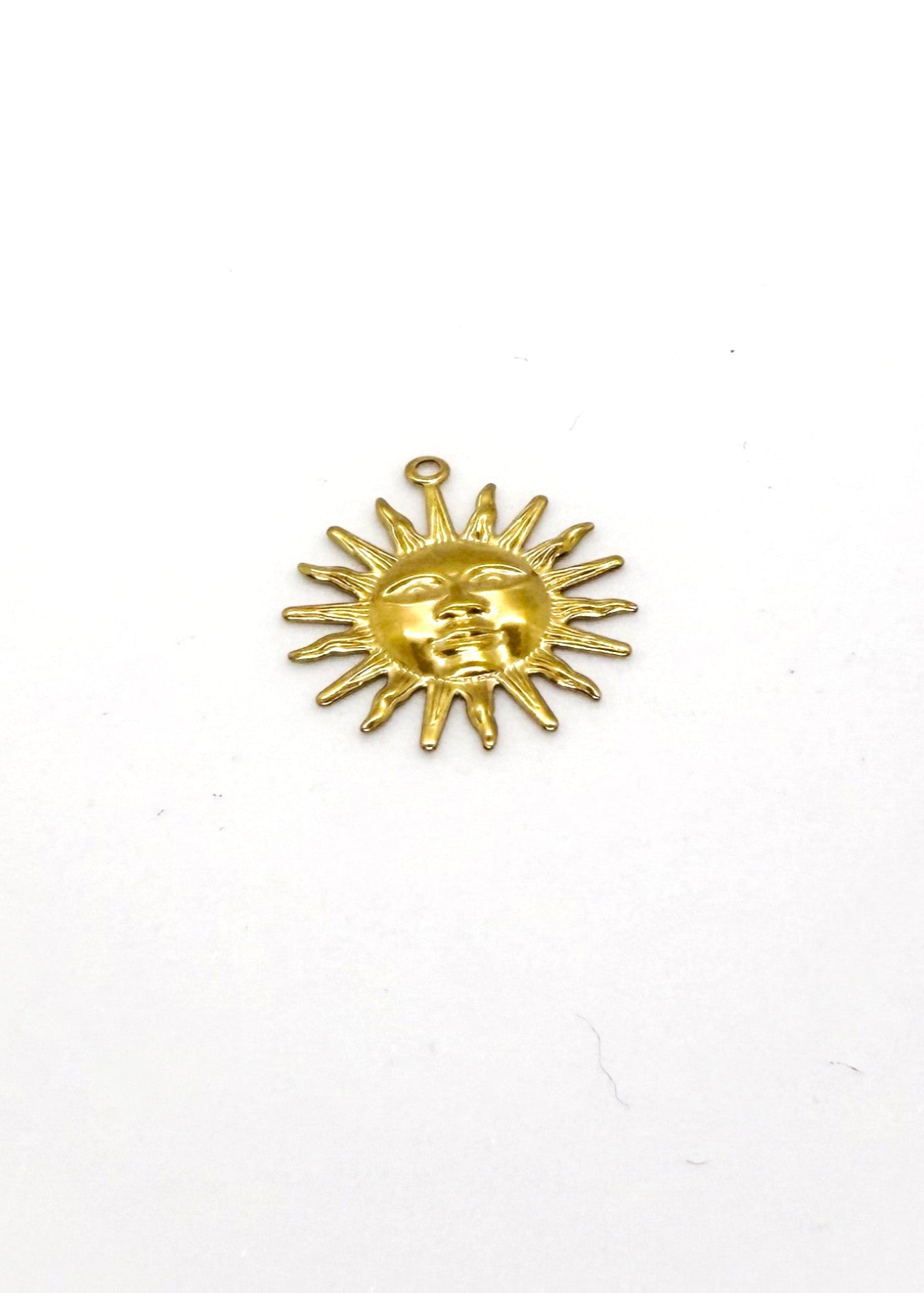 Gold sun-shaped charm on a white background
