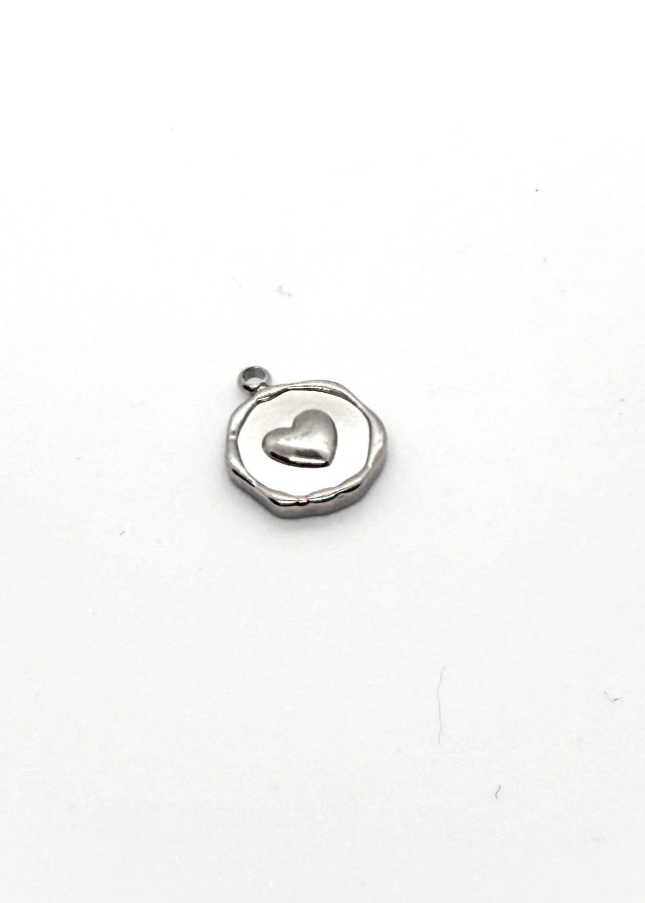 Silver stainless steel charm with a heart design on a white background