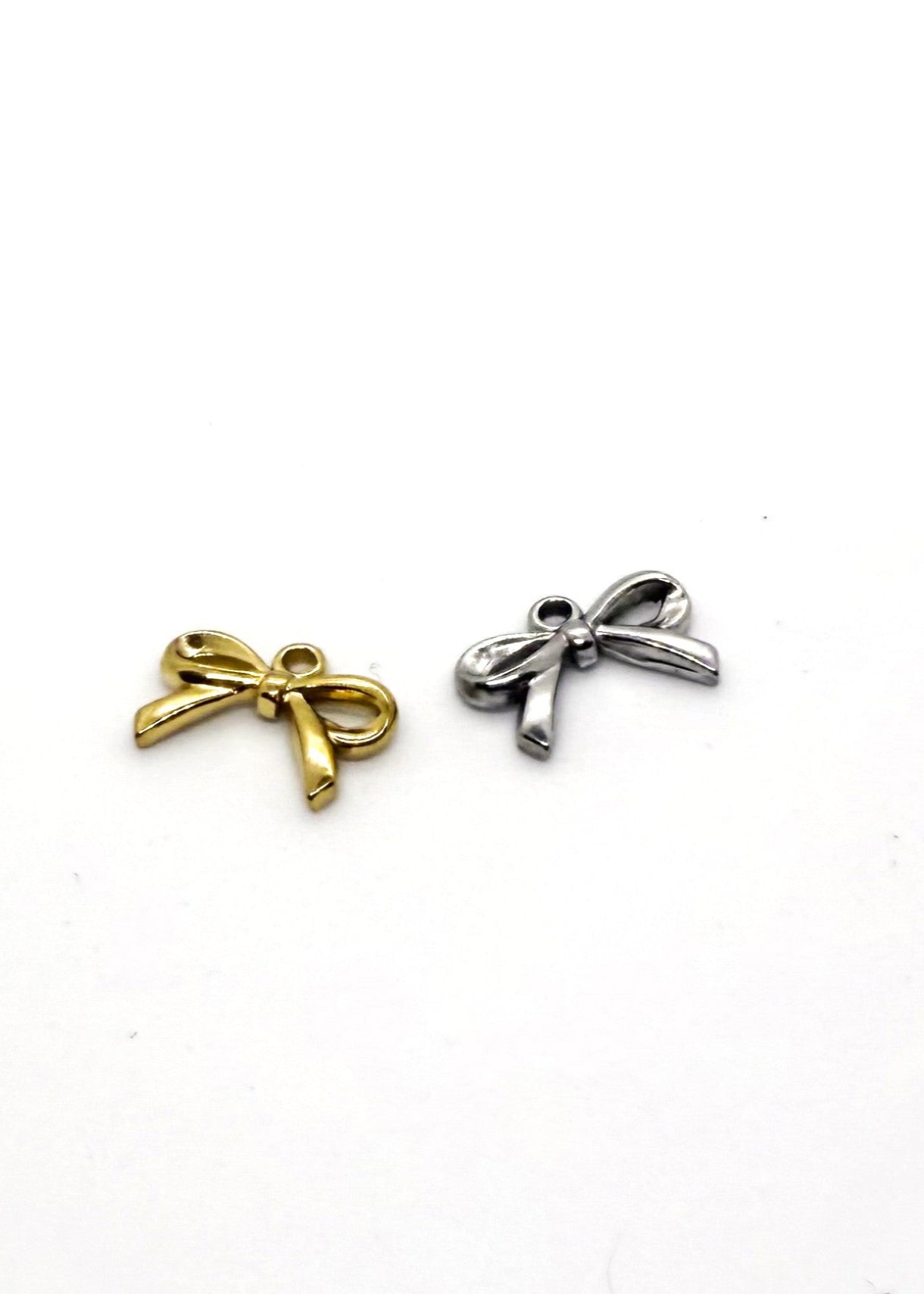 Two stainless steel bow-shaped charms, one gold and one silver, on a white background.