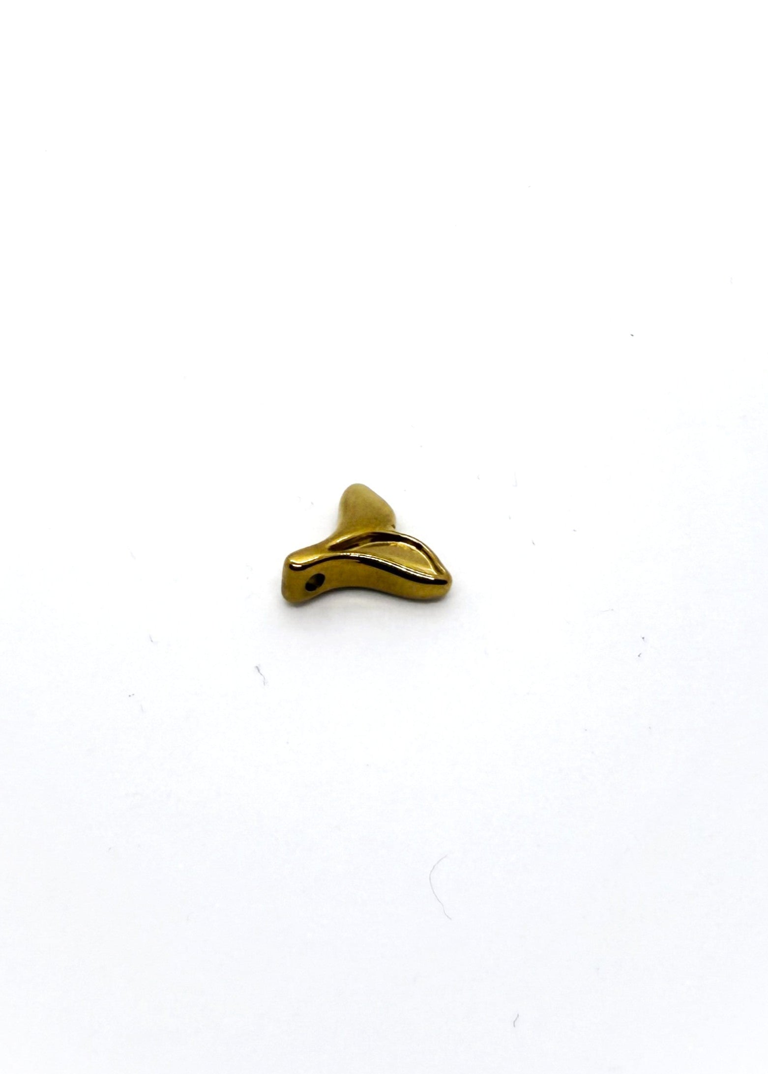 Gold-colored fish tail charm on a white background