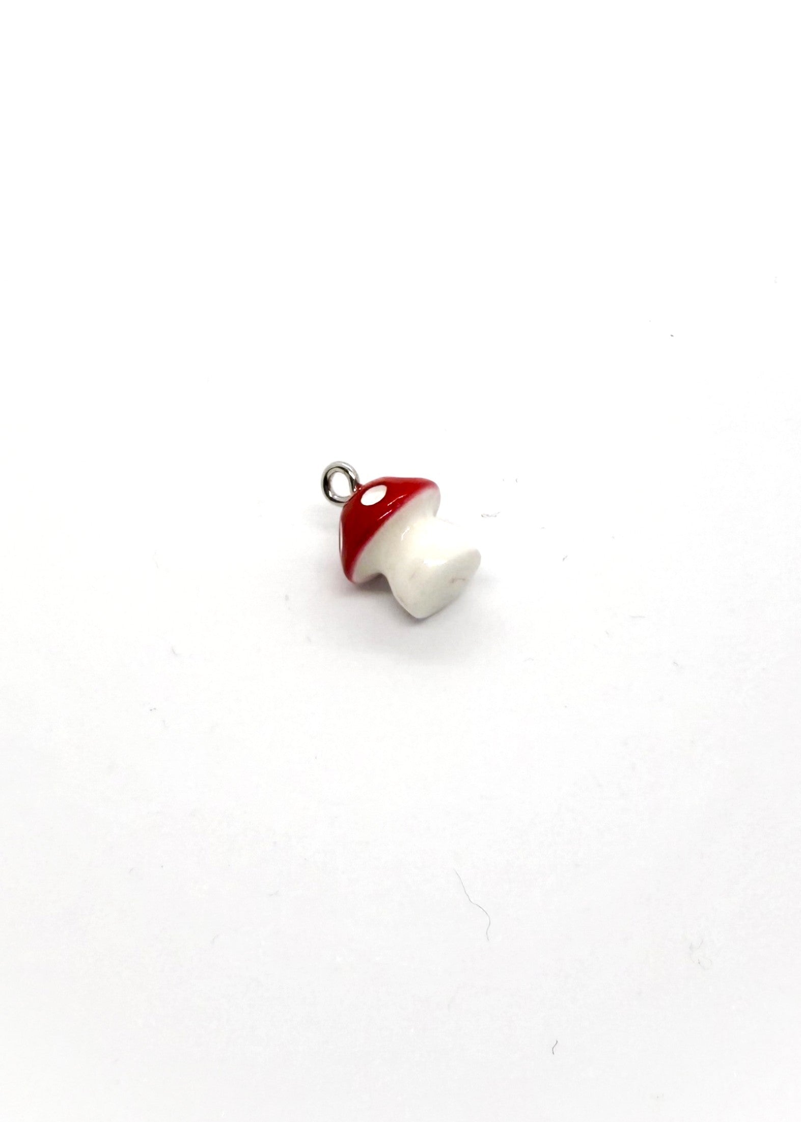 Mushroom-shaped charm with red cap and white body on a white background