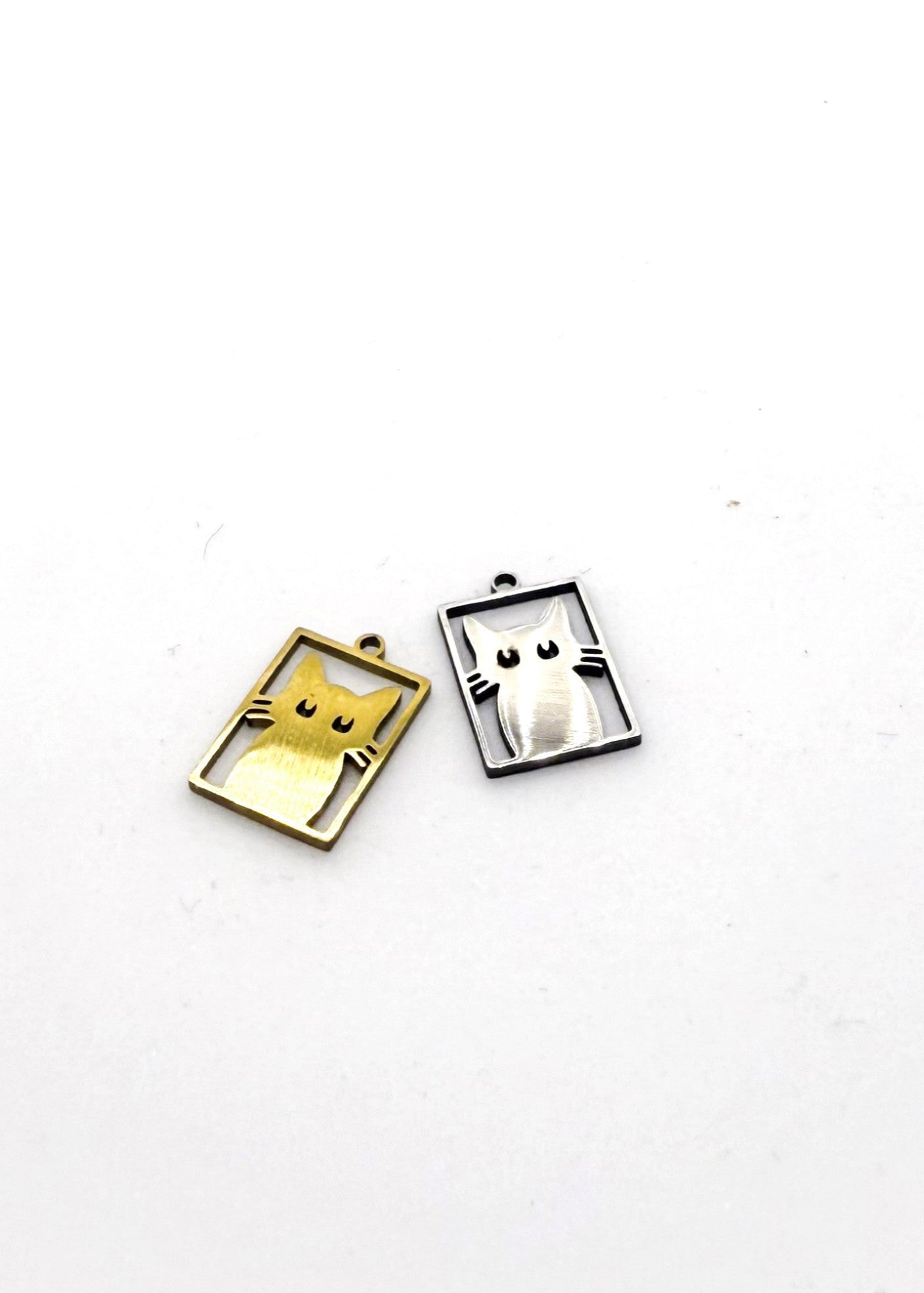 Two Stainless steel cat-shaped Charms, one gold and one silver, on a white background.
