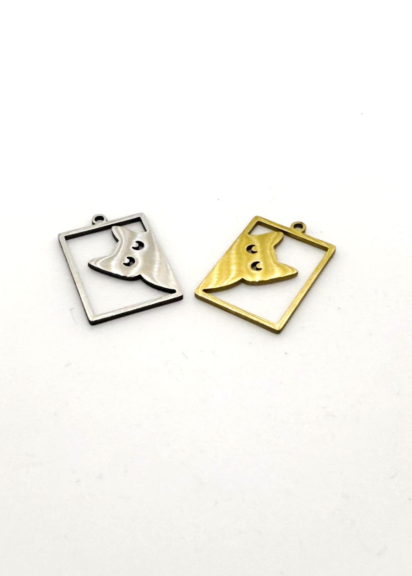 Two stainless steel big cat charms, one silver and one gold, on a white background
