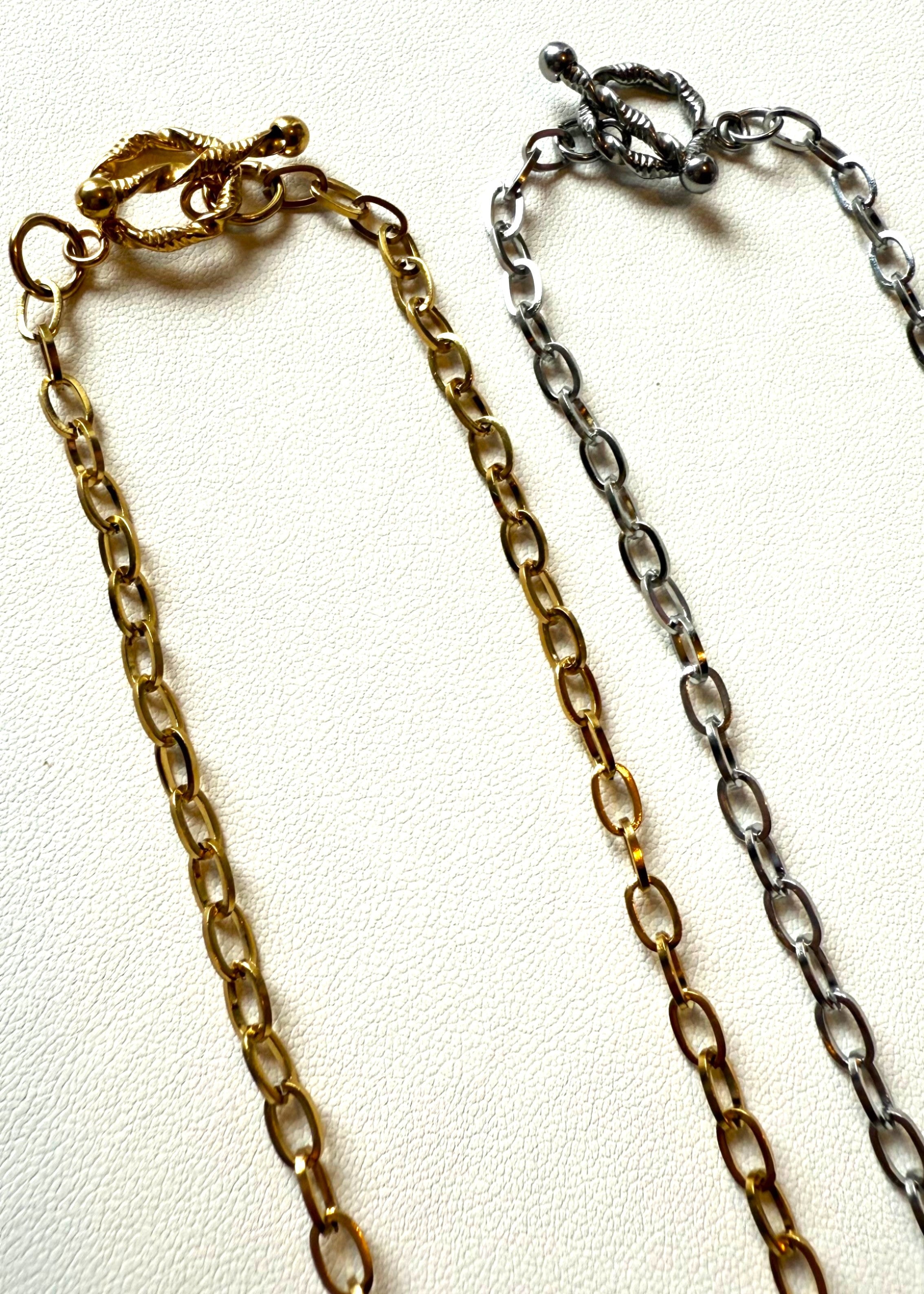 Two chain necklaces in gold and silver on a white background