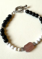 Bracelet with black, white, and brown beads on a beige background