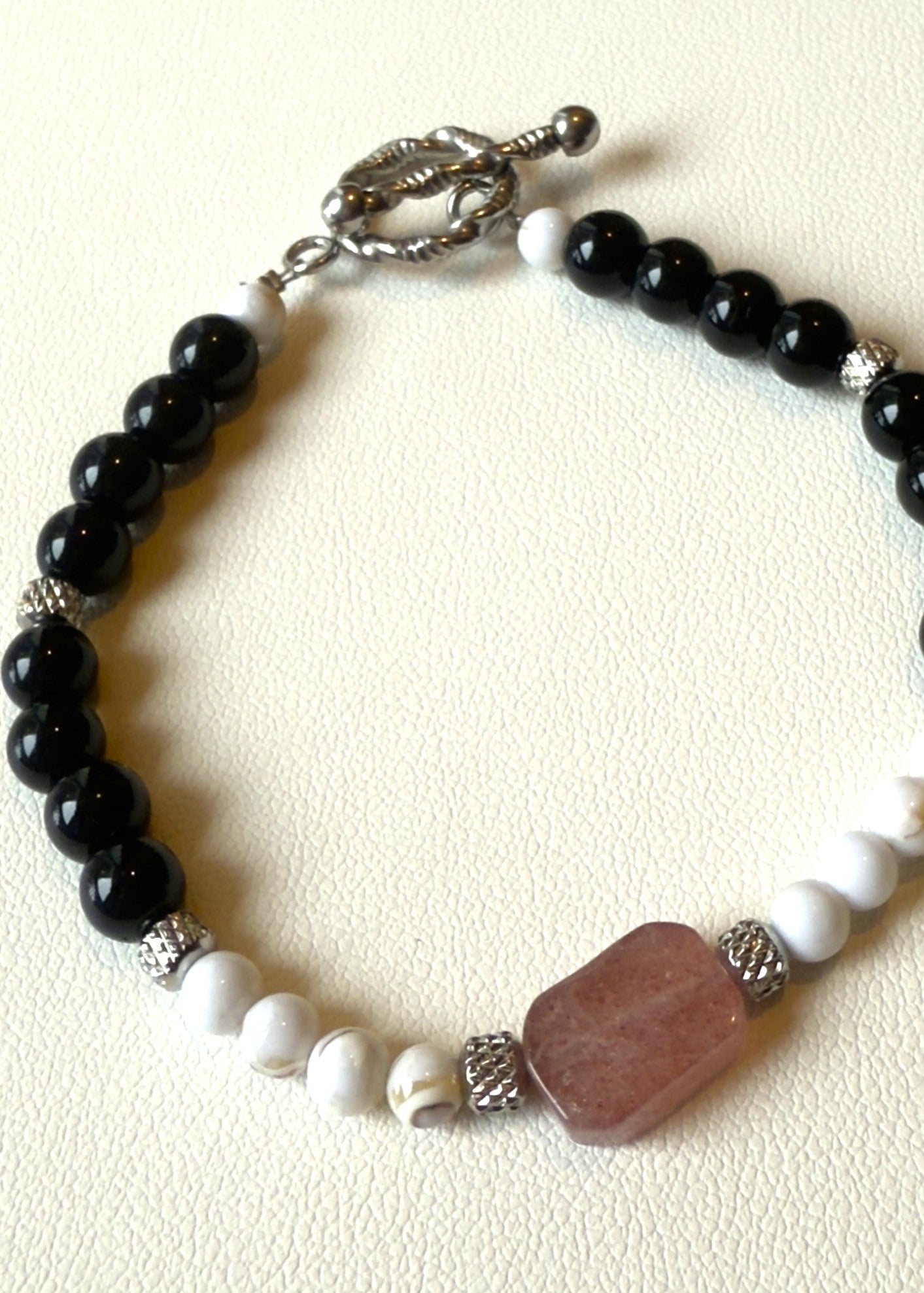 Bracelet with black, white, and brown beads on a beige background