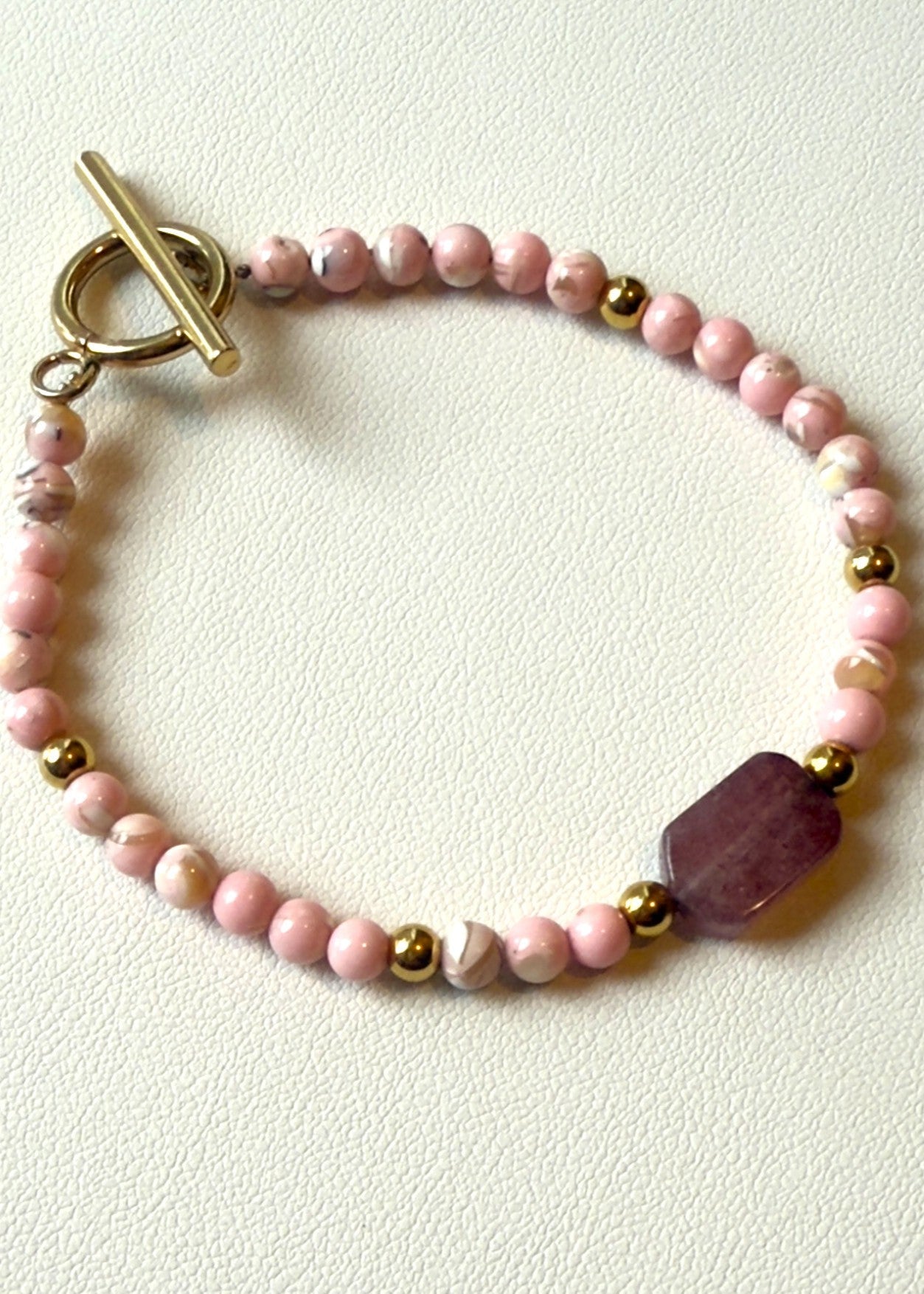 Beaded bracelet with pink and gold beads on a white background
