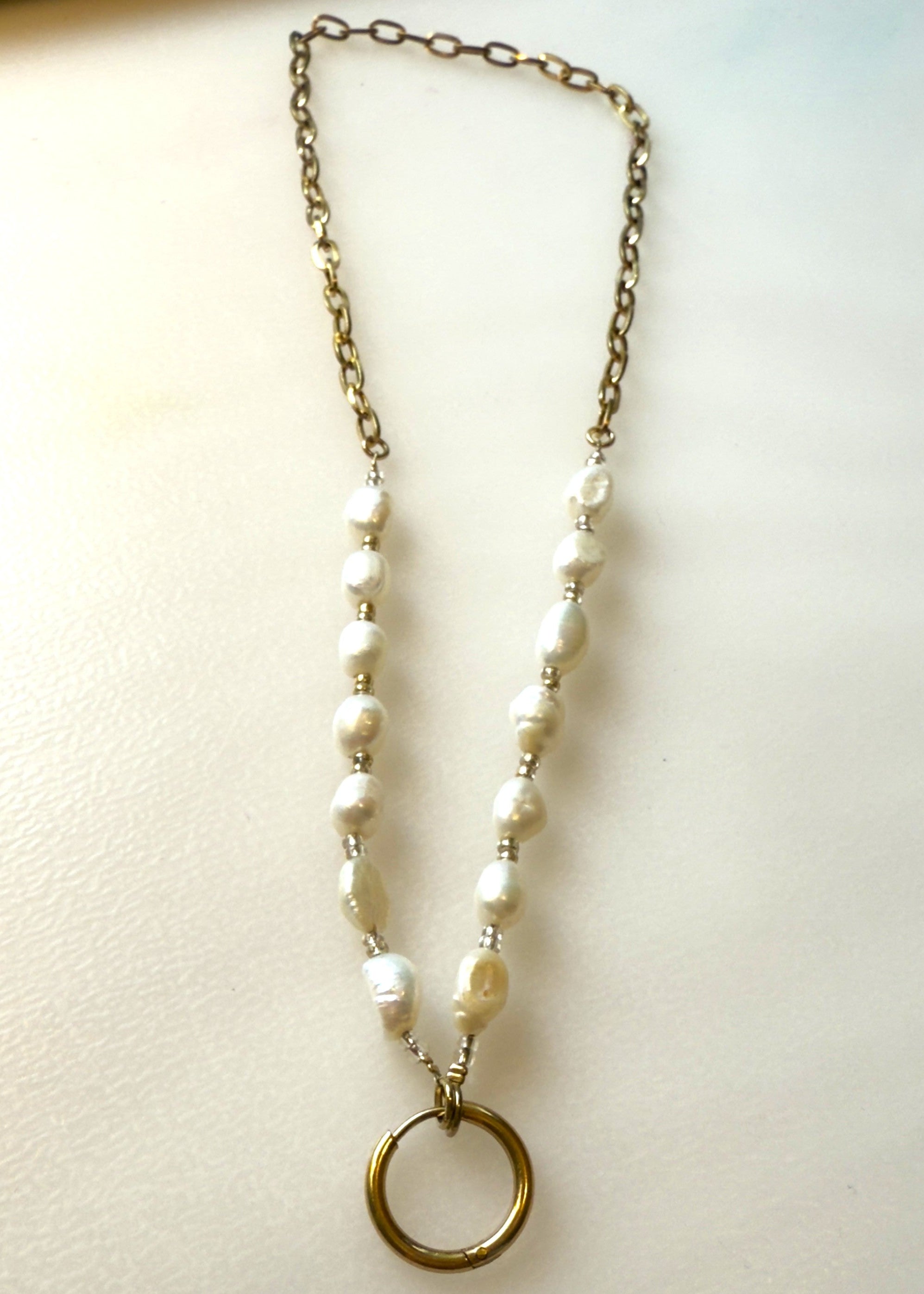 Freshwater pearl and oval link chain with a gold ring charm holder on a white background