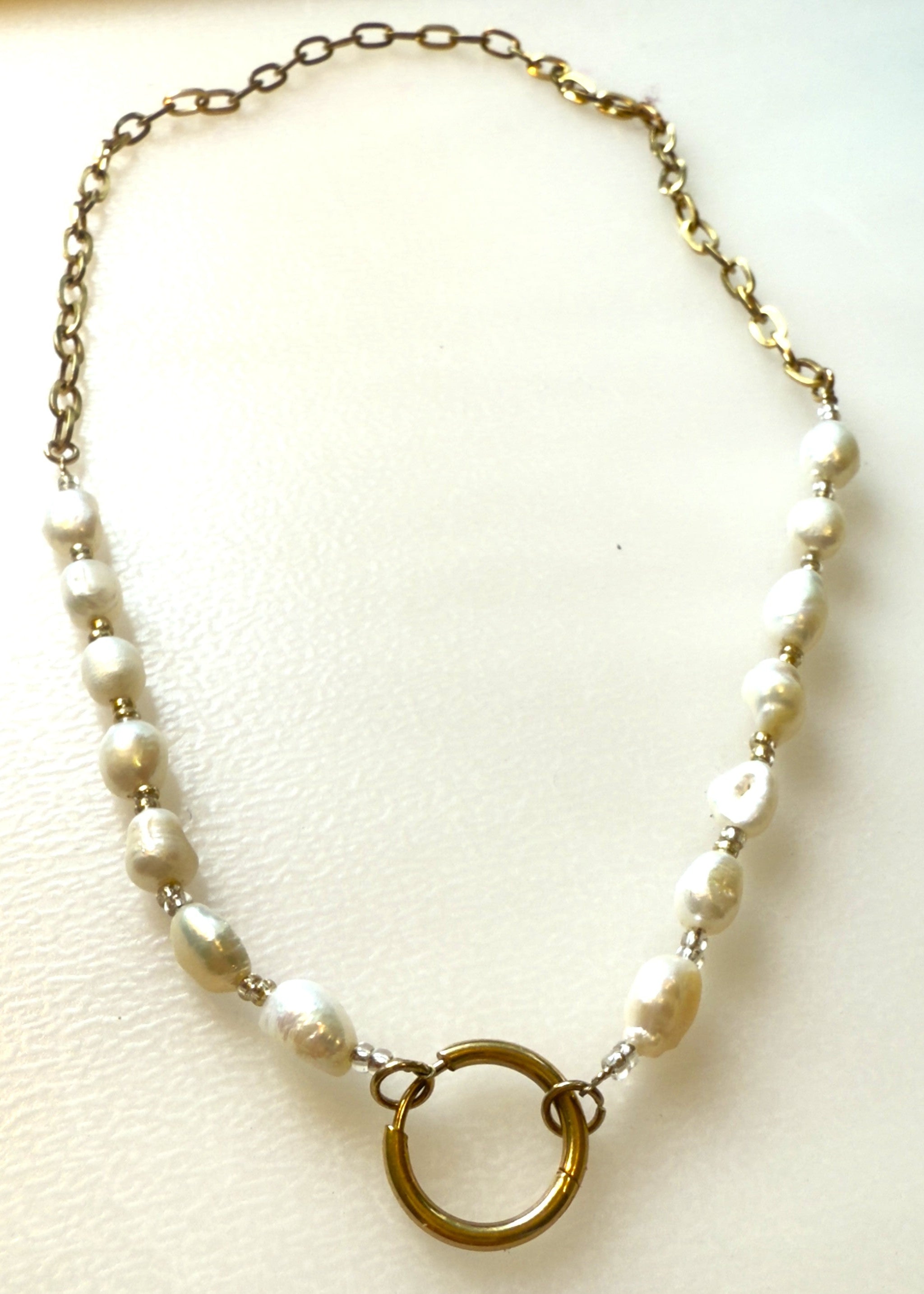 Freshwater pearl and oval link chain with a gold ring charm holder on a white background